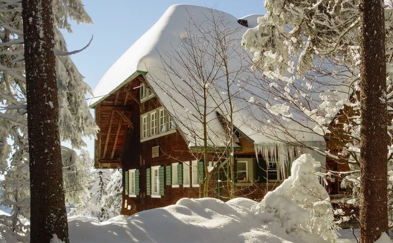 Alpine lodge with roof thickly covered in snow