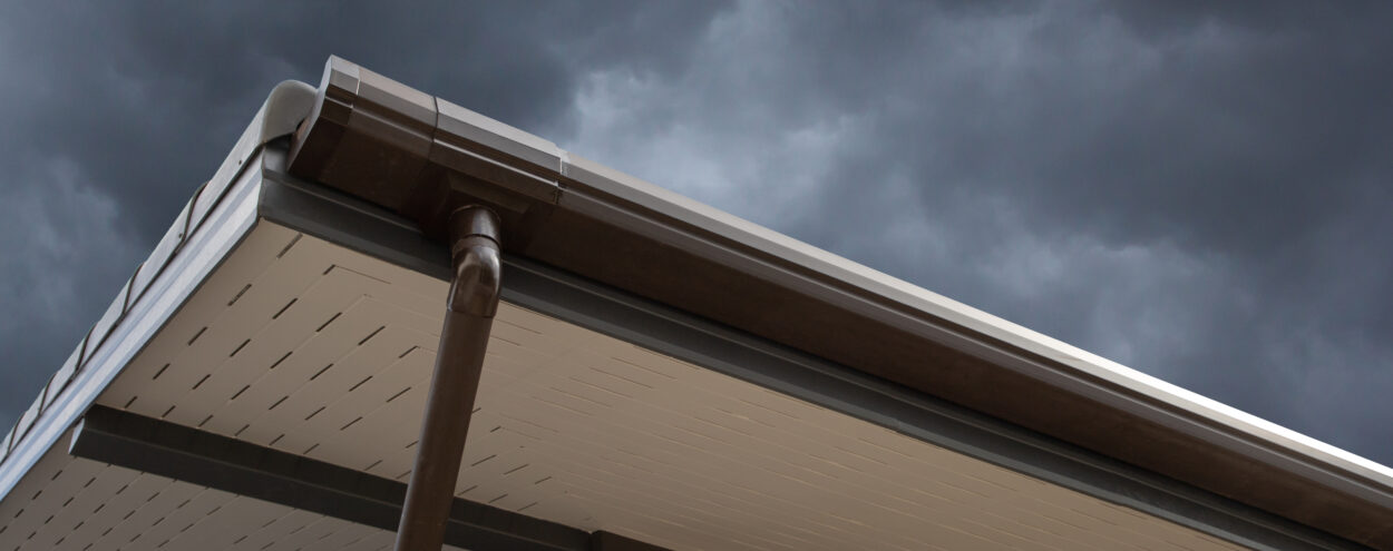 Low angle shot of a rain gutter with a dark sky behind.