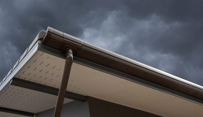 Low angle shot of a rain gutter with a dark sky behind.