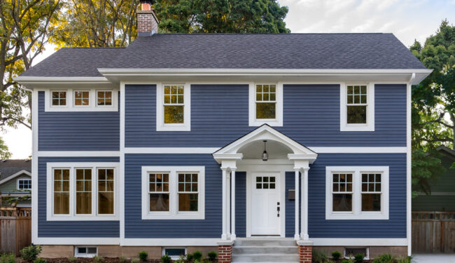An exterior shot of a colonial with dark blue siding.