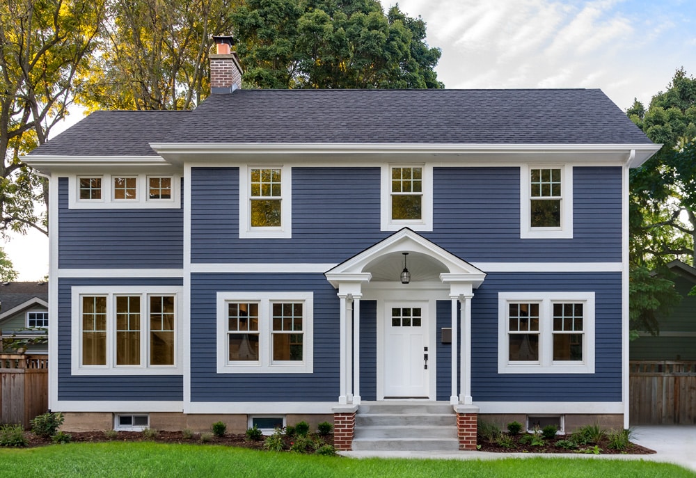An exterior shot of a colonial with dark blue siding.
