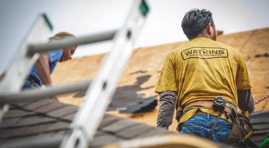 Watkins worker in a yellow t-shirt replacing a roof